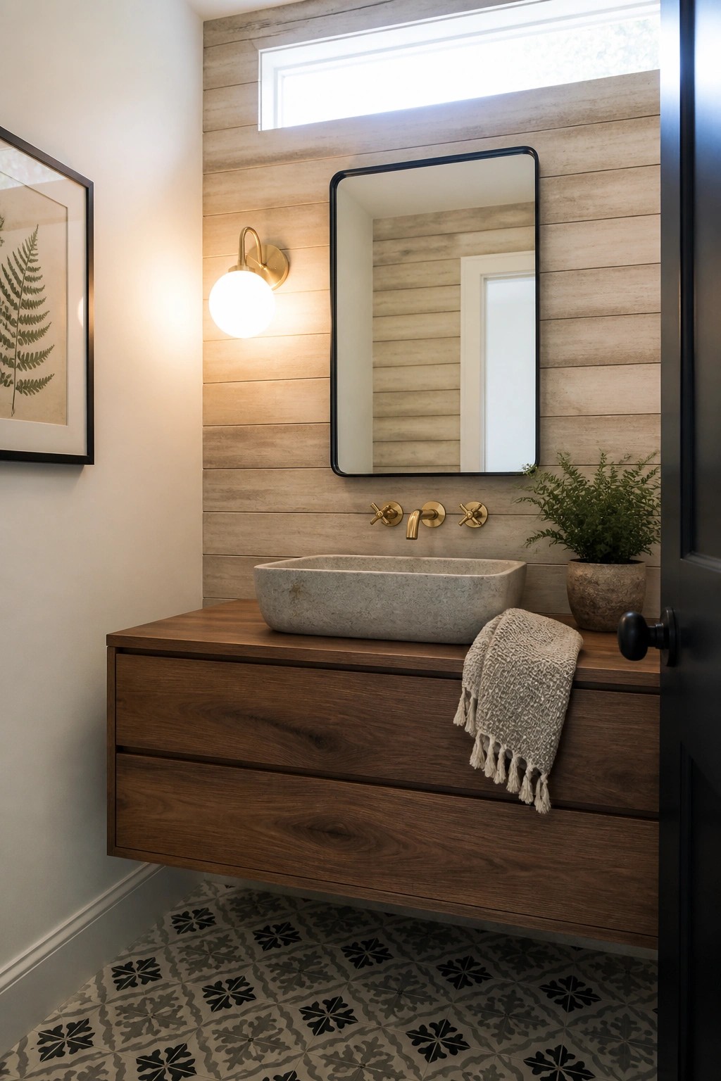 A bathroom interior showing a horizontal light wood plank accent wall behind a floating dark wood vanity with a stone vessel sink and black framed mirror.