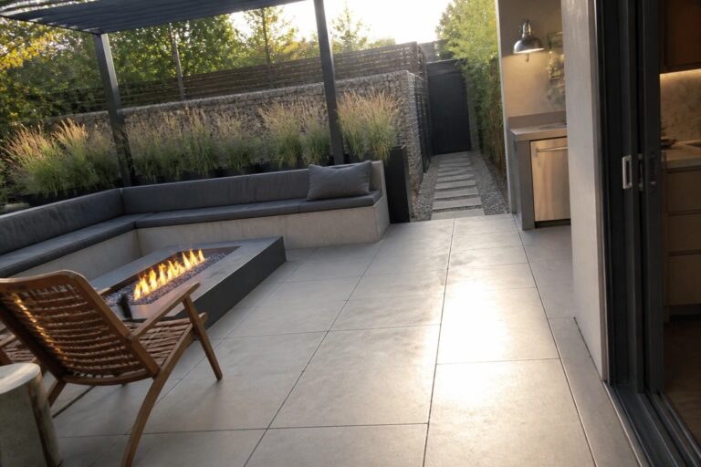19 Low-Maintenance Patio Ideas Built Around Durable Hardscaping Modern patio with fire pit, wooden chairs, built-in seating, and potted plants
