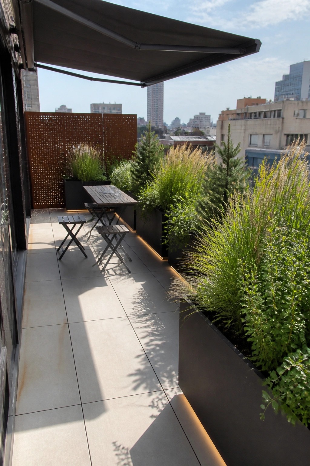 Modern balcony with wooden table, stools, lush planters, and city skyline view.