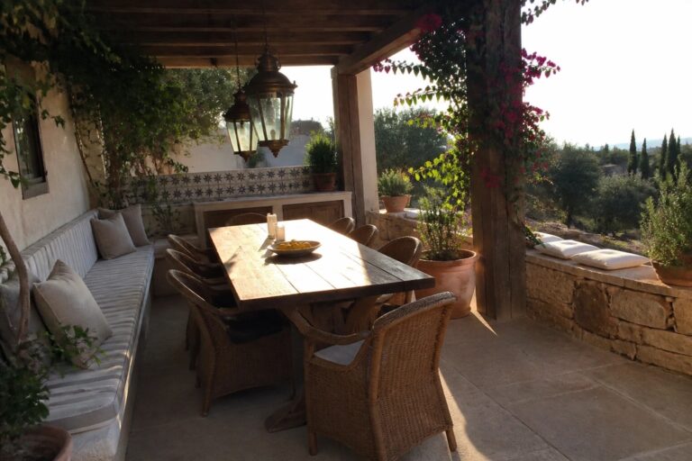 23 Smart Patio Extension Ideas for Adding an Outdoor Dining Zone Rustic wooden table with woven chairs on sunny patio overlooking hills with hanging lanterns and plants.