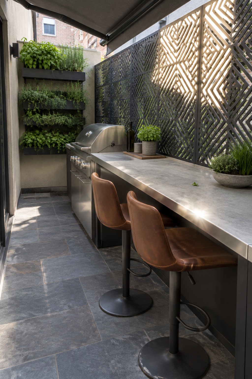 Outdoor patio with concrete bar counter, two brown leather bar stools, stainless steel grill, and black metal privacy screens featuring geometric cutout patterns.