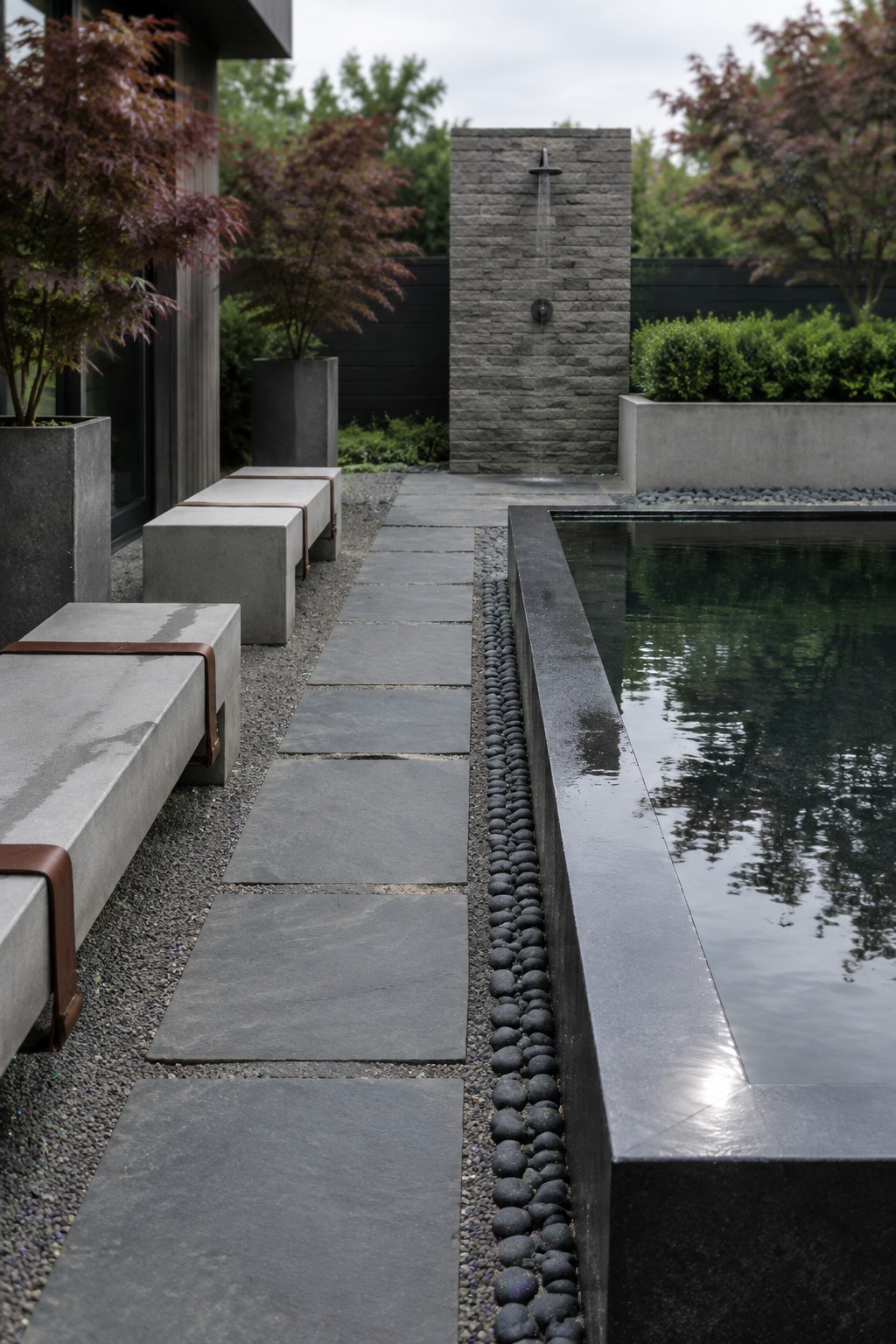 Modern garden with stone path, concrete benches, reflecting pool, and outdoor shower wall.