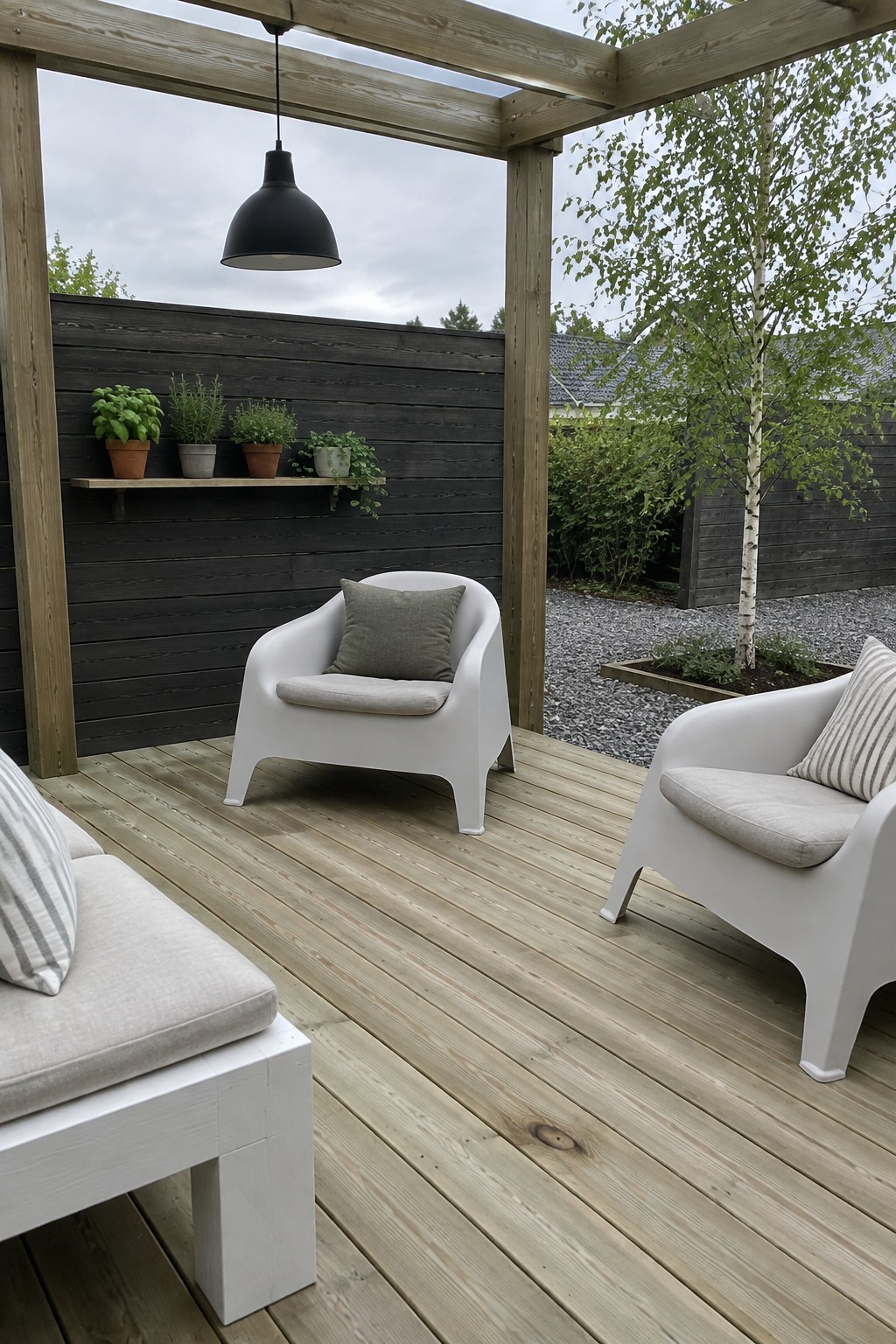 A wood deck beneath a timber pergola has white outdoor chairs, a dark privacy fence, and potted plants.
